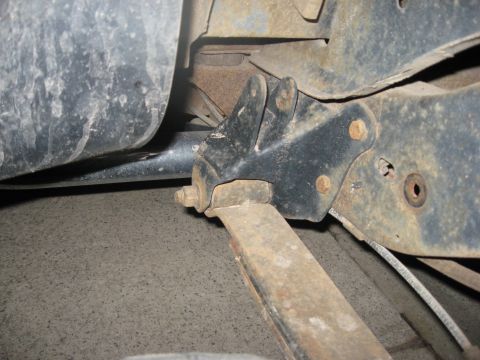 1986 Ford Bronco - Close-up view of the rusty undercarriage and suspension parts of a vehicle.