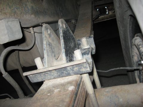 1986 Ford Bronco - Close-up view of the leaf spring and suspension bracket assembly on the underside of a vehicle.