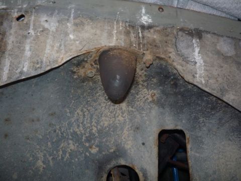 1969 Lincoln Continental - Close-up view of a vehicle's undercarriage, revealing a dark, conical part and signs of rust.
