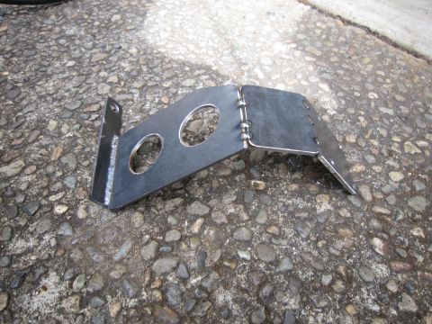 2008 Jeep Wrangler - A shop-fabricated bare steel mounting bracket lying on wet exposed-aggregate concrete, made from two plates joined by a row of stacked-dime…