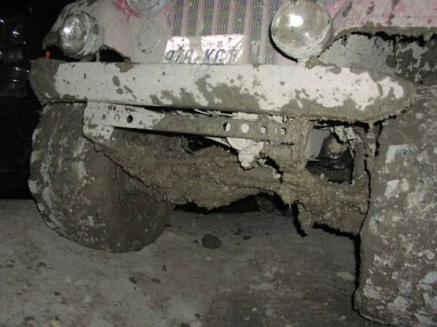 1981 Ford Bronco - Vehicle front end heavily covered in mud, obscuring details of the make and model.