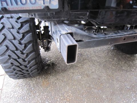 2008 Jeep Wrangler - Close-up of a vehicle's rear frame showing a hitch receiver and tire; Evergreen State license plate is visible.