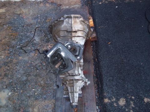 1989 Ford F-150 - A transmission assembly is shown resting on wooden planks on a rough surface.