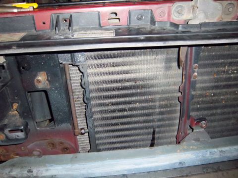 1989 Ford F-150 - The radiator and condenser assembly of a vehicle is visible, covered in dust and grime.