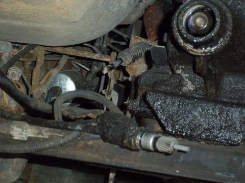 1989 Ford F-150 - Close-up view of the undercarriage of a vehicle, revealing mechanical components covered in grease and grime.