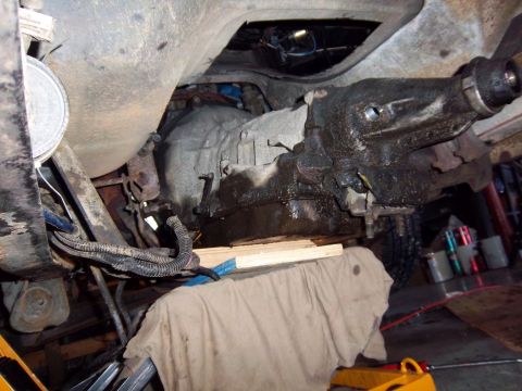 1989 Ford F-150 - A close-up view of a vehicle's transmission and undercarriage components, supported by wood blocks and cloth.