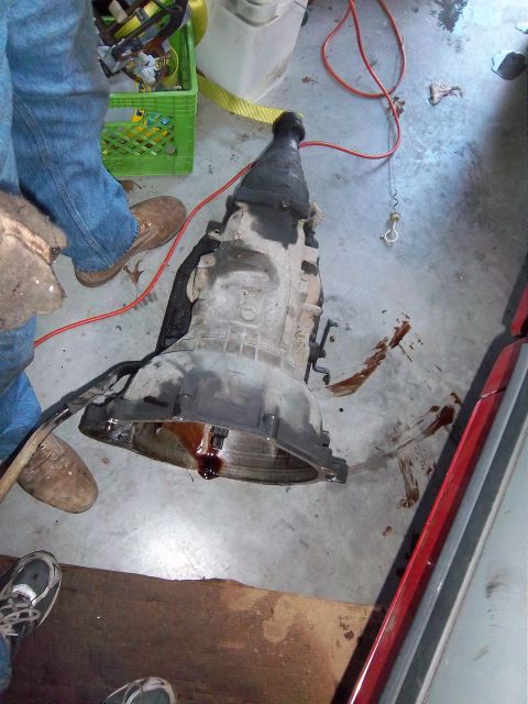 1989 Ford F-150 - Automatic transmission with fluid leaks on a concrete floor, with a person's legs visible.