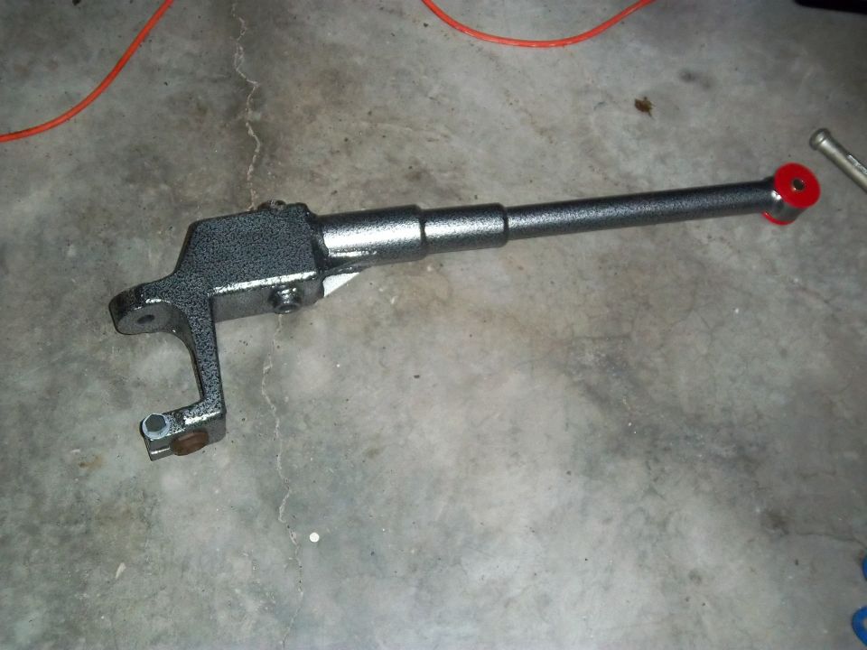 Gray metal suspension arm with red bushing on concrete floor