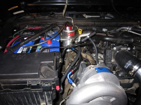 2008 Jeep Wrangler - Aftermarket supercharger installed in an engine bay, showing the battery and wiring.