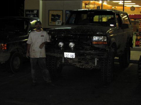 1981 Ford Bronco - A man poses next to a dirty black SUV, with another vehicle partially visible on the left.