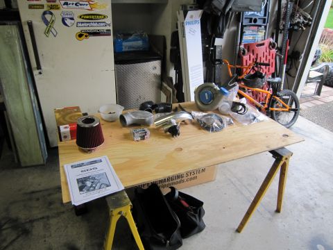 2008 Jeep Wrangler - Various automotive parts are organized on a workbench, with a bicycle visible in the garage setting.