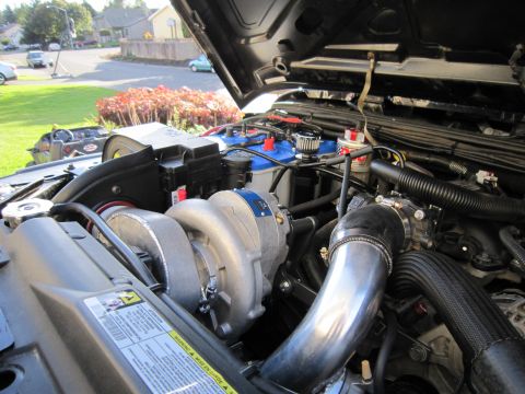 2008 Jeep Wrangler - Close-up view of a modified engine bay a prominent supercharger and custom intake piping.