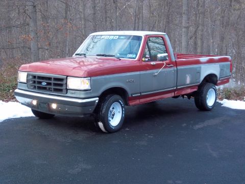 1989 Ford F-150 - This two-tone Ford truck has a white roof and white wheels, parked outdoors in a wooded area.