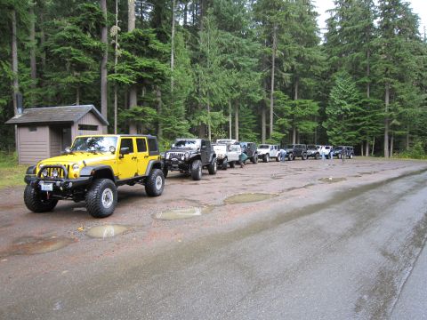 2008 Jeep Wrangler - A line of Jeeps, including a yellow Wrangler, are parked in a wooded area.