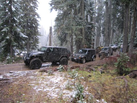 2008 Jeep Wrangler - Several Jeep Wranglers navigate a muddy forest road during a snowfall.