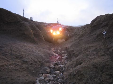 2008 Jeep Wrangler - Jeep Wrangler navigates a steep, rocky ravine, its headlights cutting through the dim light.