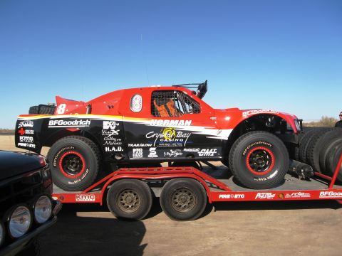 1986 Ford Bronco - A custom-built off-road truck with racing decals is transported on a trailer.