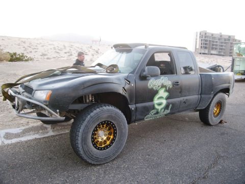 1986 Ford Bronco - A modified black truck with off-road tires and custom graphics sits parked on asphalt.