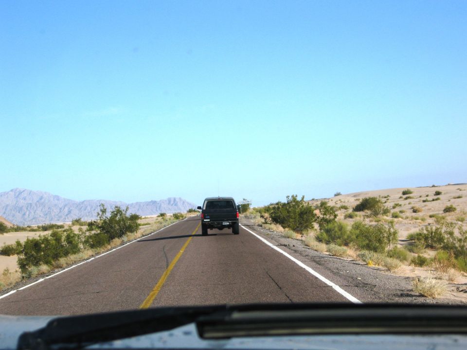 Black SUV on desert highway, seen from behind