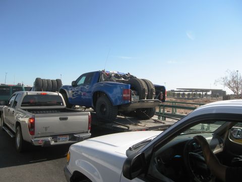 1986 Ford Bronco - A blue off-road truck is being transported on a trailer, with other vehicles around it.