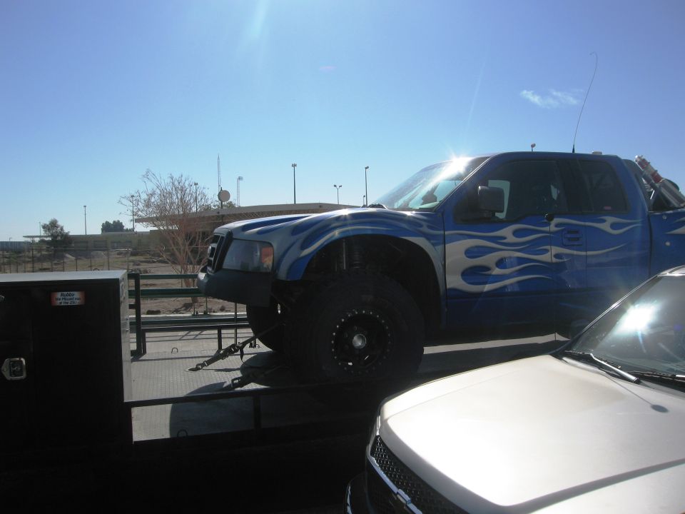 Blue pickup truck with flame decals on a flatbed trailer