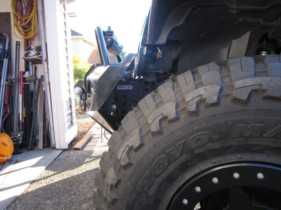 Toyo M/T tire on black beadlock wheel at the front corner of a Jeep in a garage doorway