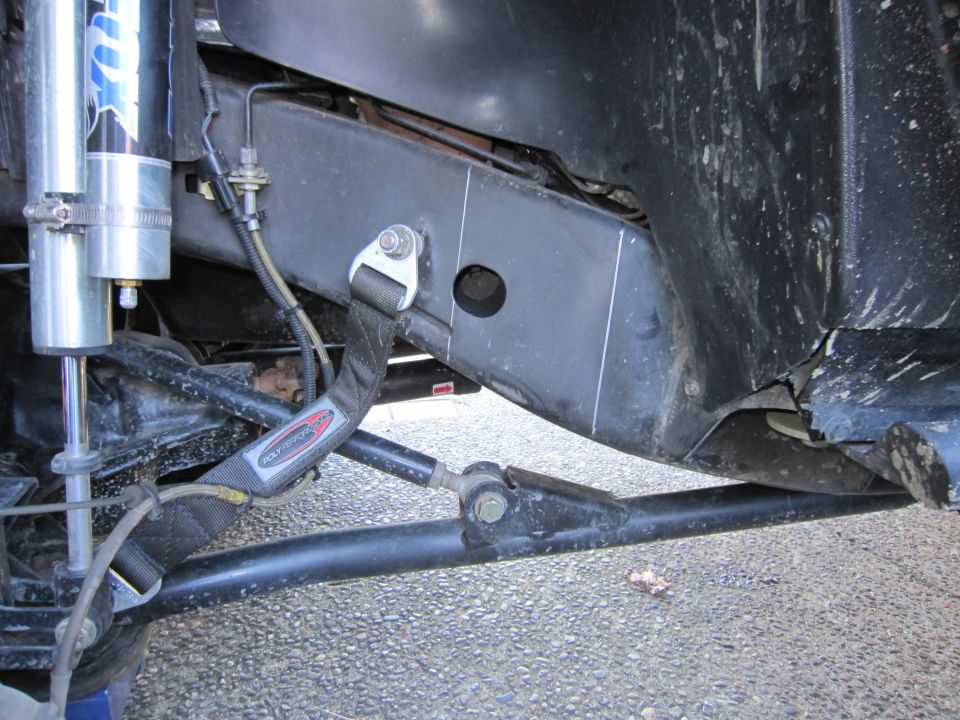 Close-up of off-road vehicle frame with Fox shocks and a tie-down strap attached
