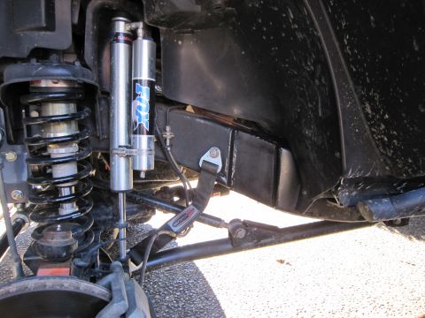 2008 Jeep Wrangler - Close-up of an off-road suspension system Fox shocks and a tie-down strap attached to the frame.