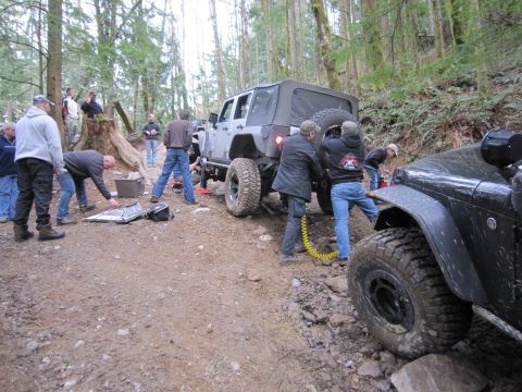 2008 Jeep Wrangler - People are working on a Jeep Wrangler on a rough forest trail, with another Jeep nearby.