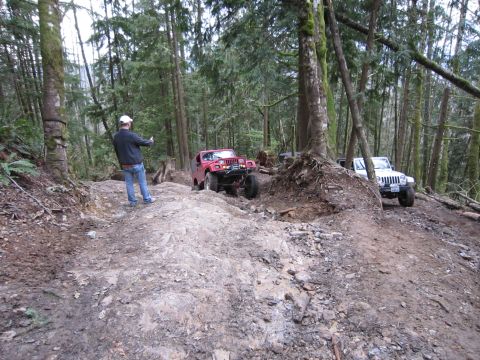 2008 Jeep Wrangler - Two Jeeps navigate a challenging off-road trail through a dense forest.