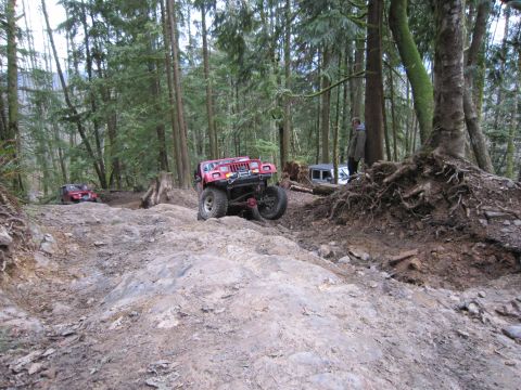 2008 Jeep Wrangler - Two red Jeep Wranglers navigate a challenging rocky trail in a forest.