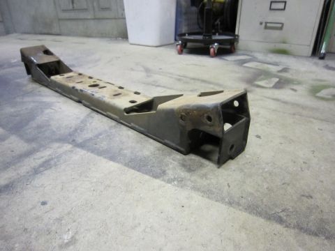 2008 Jeep Wrangler - A metal suspension component, possibly a frame or long arm, rests on a concrete floor in what appears to be a workshop or garage.