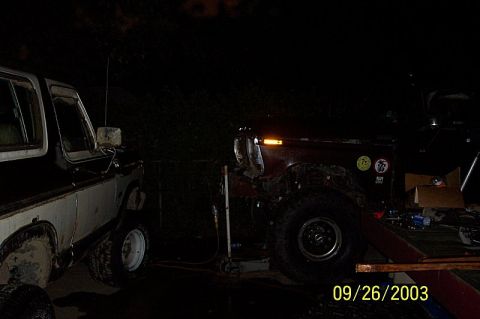 1978 Ford Bronco - Two off-road vehicles are parked outdoors at night, with one partially obscured by darkness.