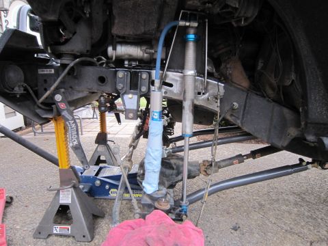 2008 Jeep Wrangler - The underside of a vehicle is shown with suspension components and steering linkage exposed for maintenance.