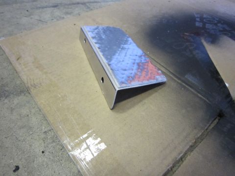 2008 Jeep Wrangler - A metal bracket is shown on a piece of cardboard, with spray paint residue in the background.