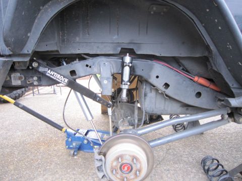 2008 Jeep Wrangler - Underside rear view of a Jeep Wrangler on a floor jack with the coil spring removed, exposing the axle, brake rotor and hub. A Currie Antir…