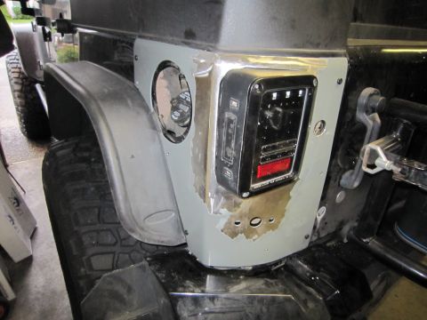 2008 Jeep Wrangler - The rear corner of a Jeep Wrangler shows modifications to the taillight housing and an exposed fuel filler door.