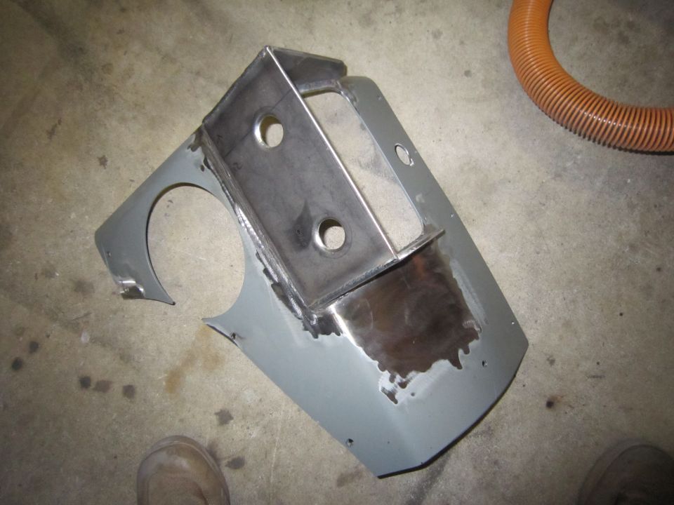 Metal bracket welded onto a gray panel with circular cutouts