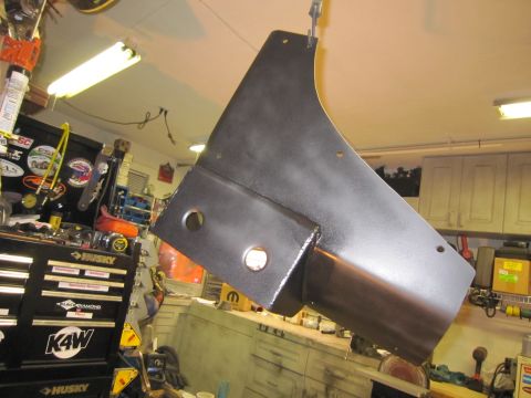 2008 Jeep Wrangler - A black metal automotive part is suspended in a workshop environment.
