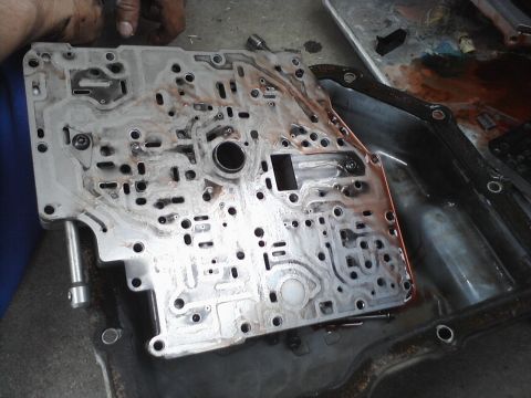 1993 Ford Taurus - A disassembled transmission valve body shows intricate channels and ports, indicating a complex internal mechanism.