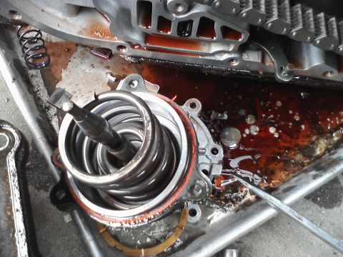 1993 Ford Taurus - Close-up of a disassembled transmission component, a prominent spring and metal parts submerged in fluid.