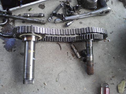 1993 Ford Taurus - Disassembled vehicle parts, including a timing chain and gears, lie on a concrete surface with various tools.