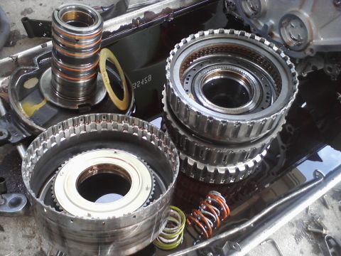 1993 Ford Taurus - Disassembled transmission parts are shown, including clutch packs and springs, in a tray with fluid.