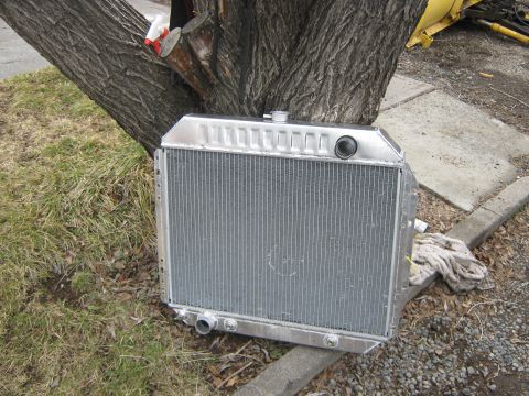 1972 Ford F-250 - An aluminum radiator is shown outdoors, leaning against a concrete curb and a tree trunk.