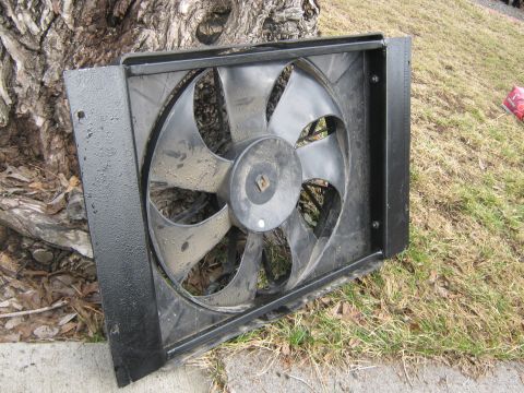 1972 Ford F-250 - A radiator fan assembly is shown outdoors, positioned in front of a tree trunk and on grassy ground.