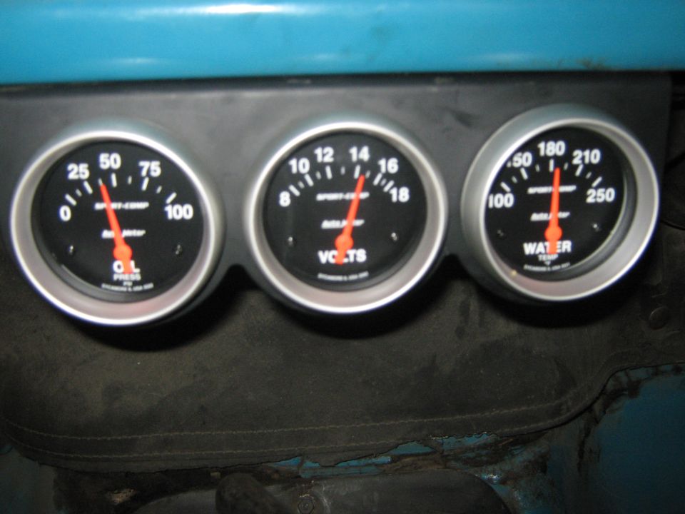 Three dashboard gauges: oil pressure, volts, and water temperature. The gauges are black with silver trim