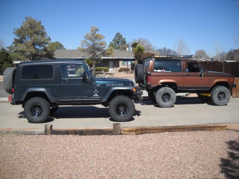 1986 Ford Bronco II - Two off-road vehicles, a Jeep Wrangler and a Ford Bronco II, are parked side-by-side in a driveway.