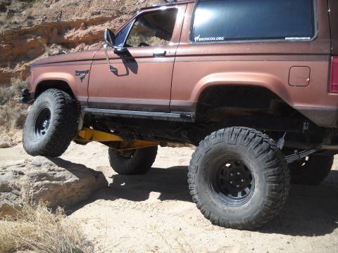 1986 Ford Bronco II - Modified 1986 Ford Bronco II navigating rough terrain with large off-road tires.