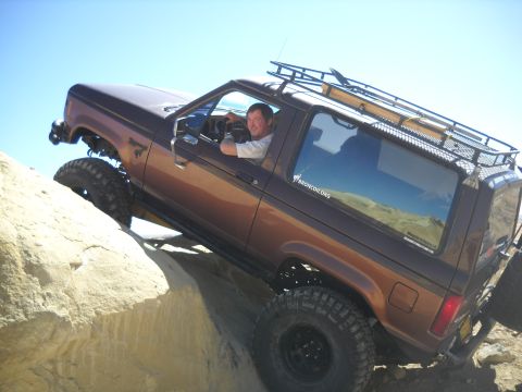 1986 Ford Bronco II - Ford Bronco II navigates rocky terrain under a clear blue sky.