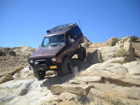 1986 Ford Bronco II - This 1986 Ford Bronco II navigates a challenging rocky trail under a clear blue sky.